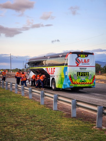 Workers arrive on a QLD mining site at dawn and grab their bags from under the bus. L&F Transfers bus LF112.