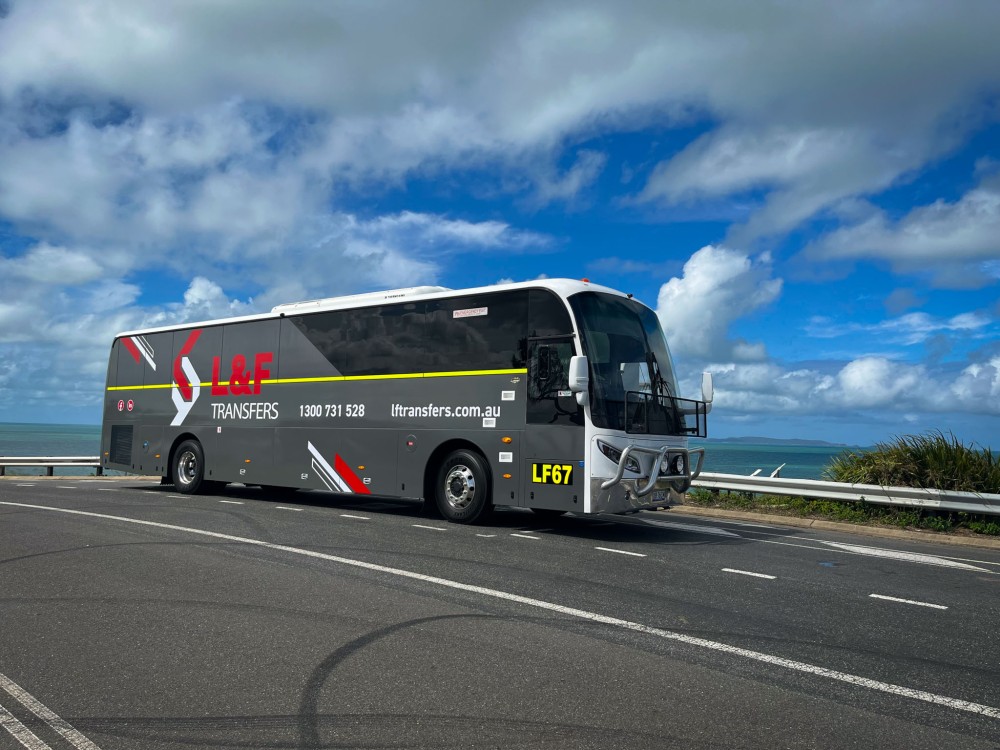 L&F Transfers luxury coach LF67 parked at Wreck Point with the ocean and Great Keppel Island in the background.