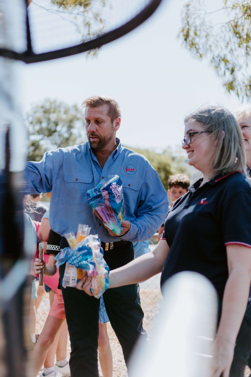 General Manager Nathan Turner and L&F staff members hand out icy poles to students on a bus charter school excursion service in Yeppoon, .